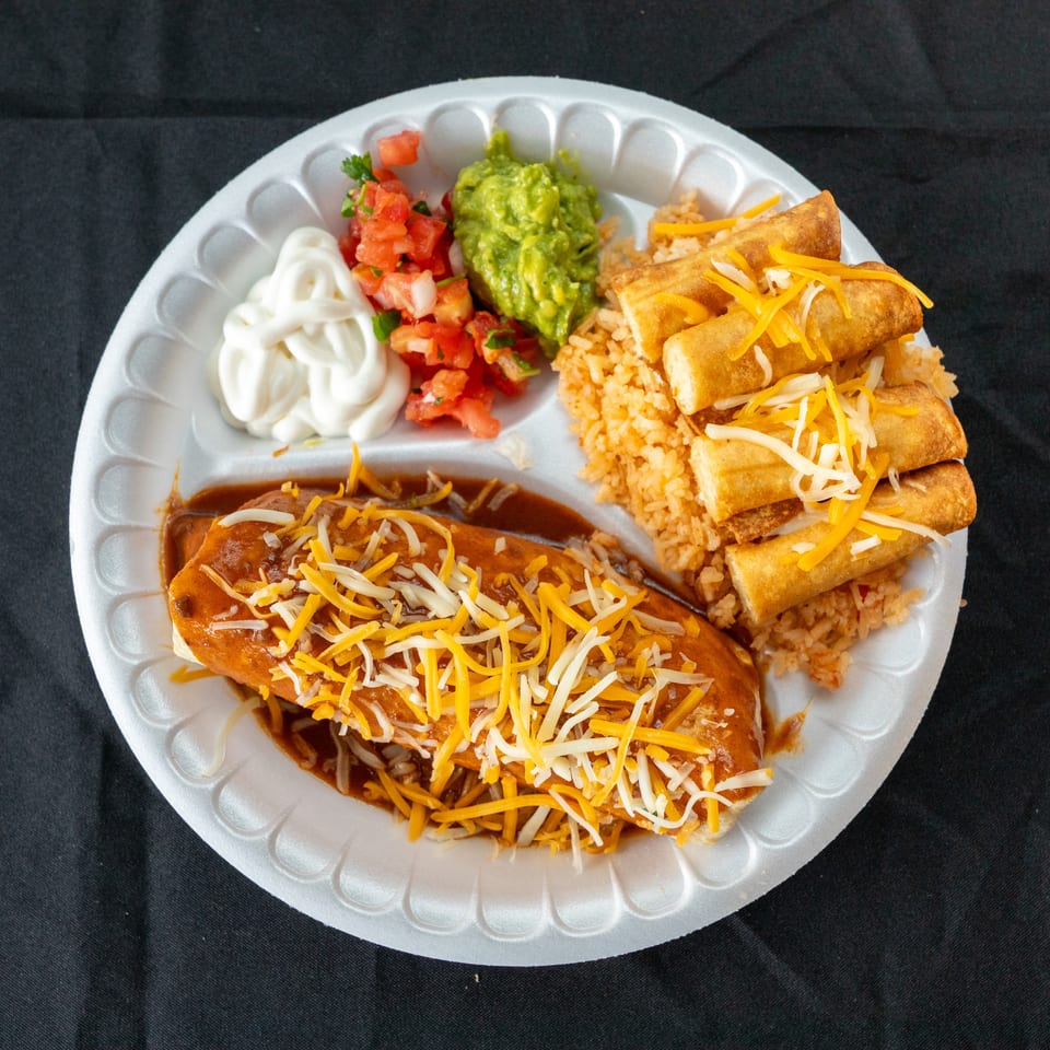 Mexican combination plate with cheese-topped enchiladas, rice, taquitos, guacamole, salsa, and sour cream.
