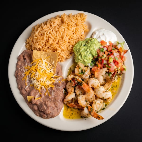Mexican seafood platter with shrimp, rice, refried beans, guacamole, pico de gallo, sour cream, and tortilla chips.